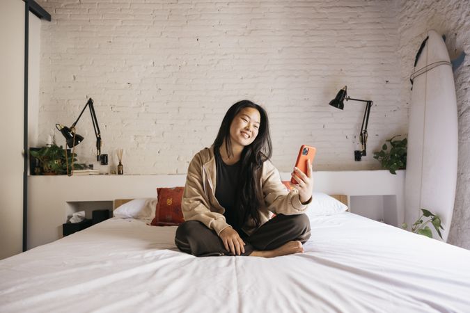 Young female with a phone on bed