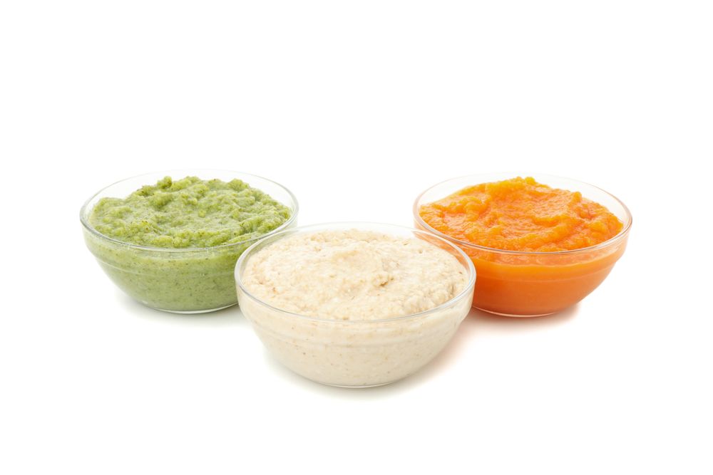 Bowls with healthy baby food isolated on plain background