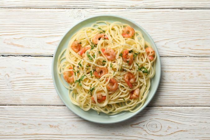 Plate with tasty pasta and shrimps on wooden background, top view