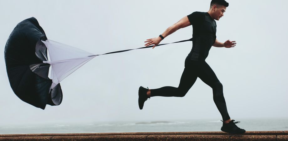 Strong man doing workout using resistance parachute outdoors
