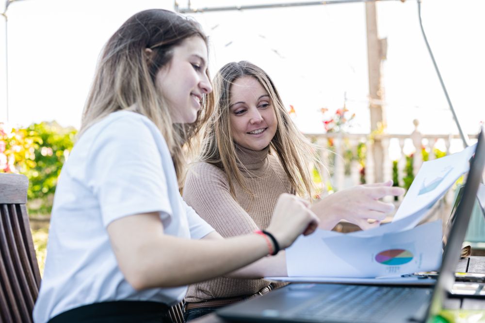 Female coworkers reviewing accounts and graphs making forecast for the next year of the company