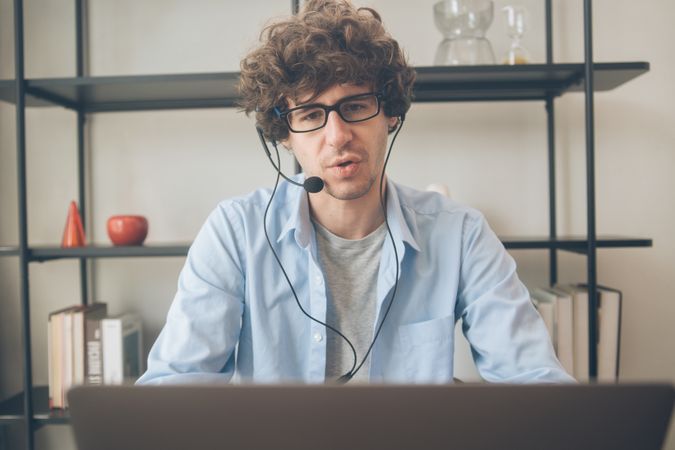 Male telemarketing talking on head set in front of laptop on desk