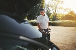 Man packing his clubs into car after a game