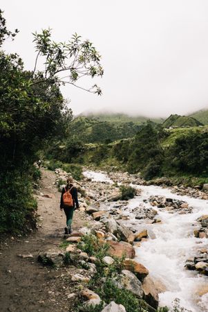 Female hiker walking next to brook in Peru mountains