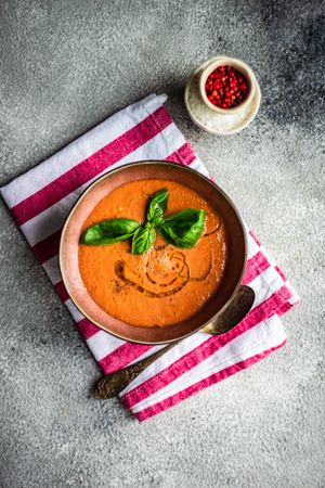 Top view of delicious tomato soup with oil garnish and basil leaves
