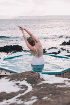 Woman sitting in pool near stones