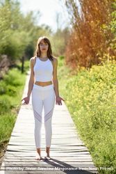 Female wearing light sport clothes standing on wooden walkway in park 5k2XW0