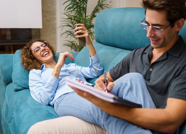 Happy couple laughing together over couch in living room