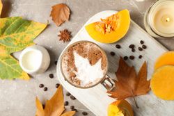 Composition with glass cup of pumpkin latte on gray background