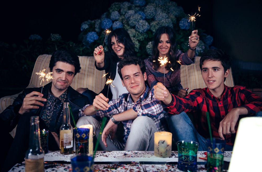 Smiling friends holding sparklers at an evening party