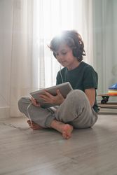 Focused preteen boy using tablet on floor in room