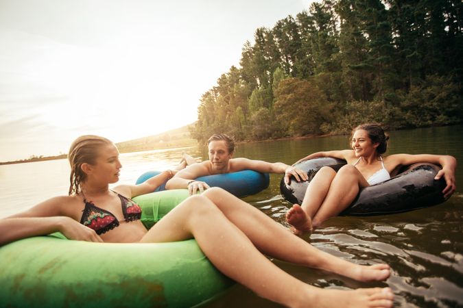 Portrait of young friends floating on lake with inflatable rings