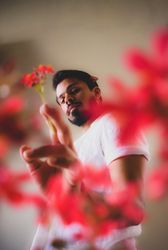 Portrait of man holding red flower against light background