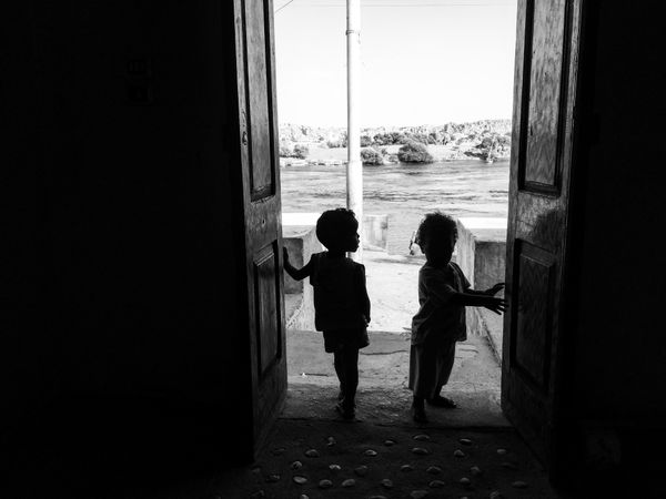 Monochrome photo of two children standing at the door in Aswan, Egypt