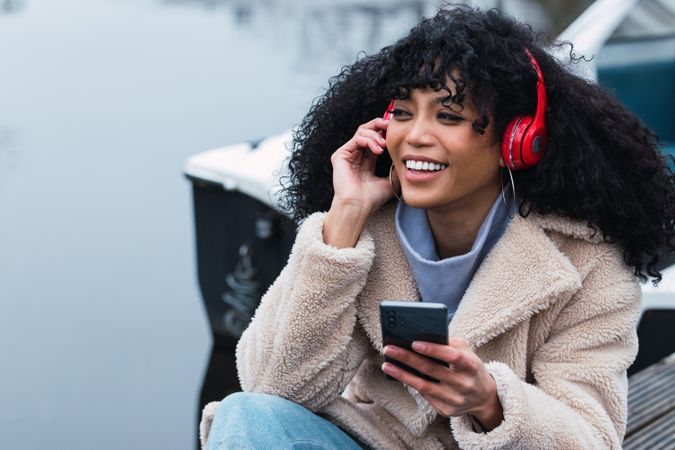 Cheerful woman listening to music at lakeside