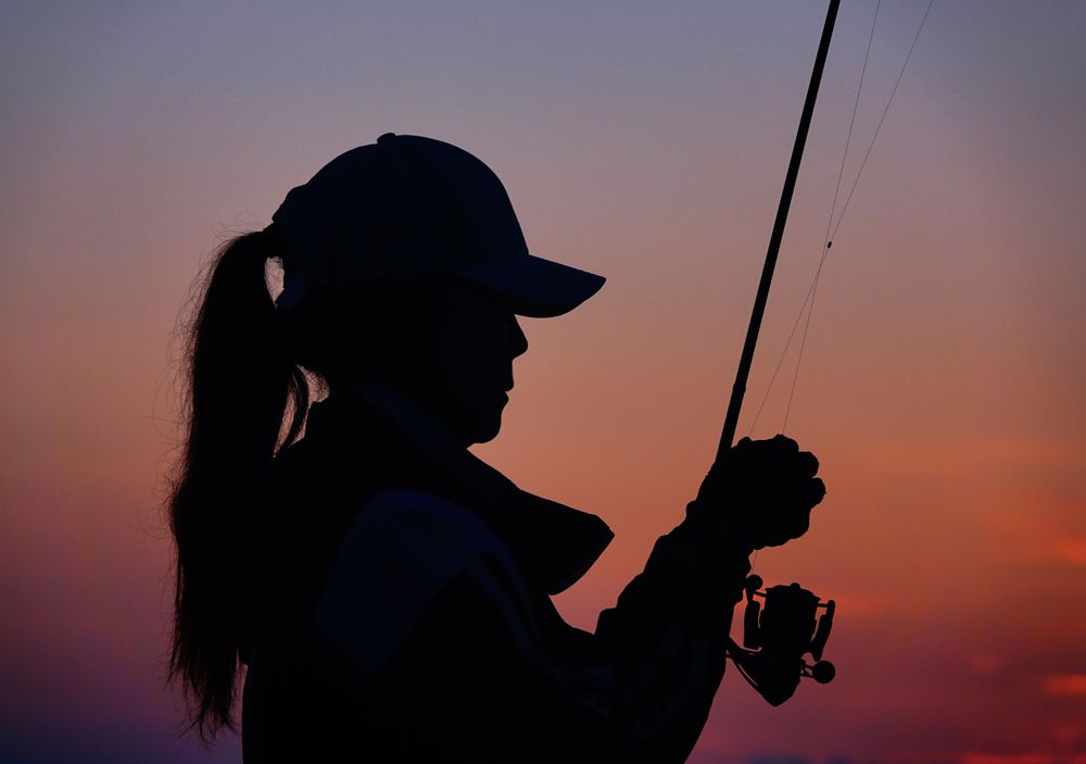 Silhouette of woman holding fishing rod