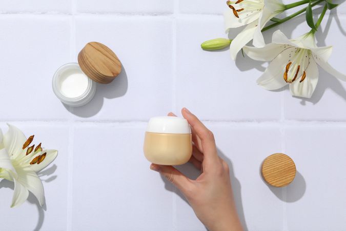 A jar of hand cream with flowers on a light background.
