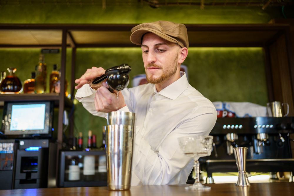 Bartender squeezing lemon juice into a shaker for cocktail
