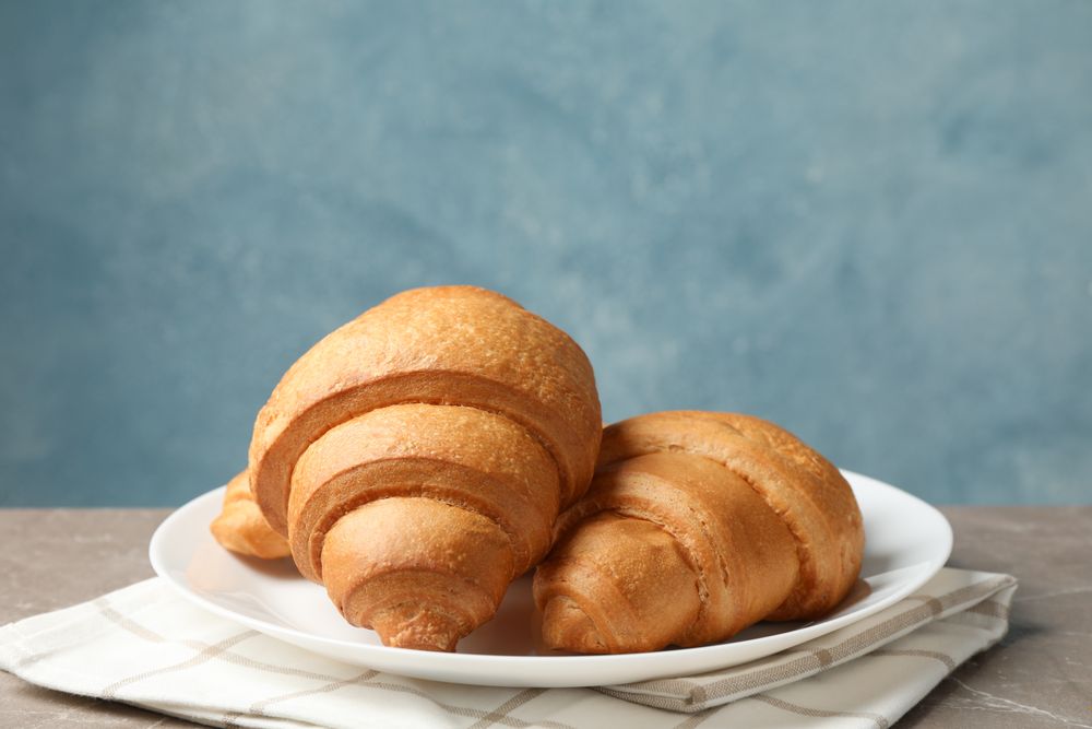 Plate with croissants on grey table, in blue room space for text