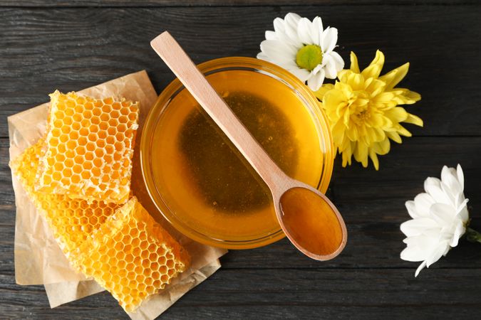 Honey, chrysanthemum and chamomile flowers on wooden background, top view