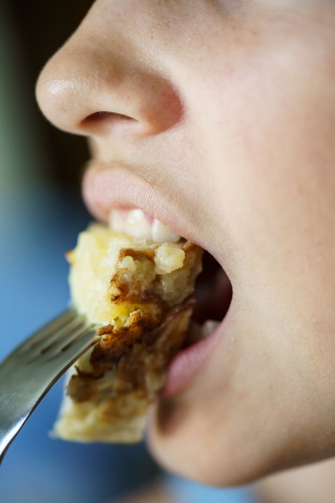 Crop of teenage girl eating fresh delicious Spanish potato omelette