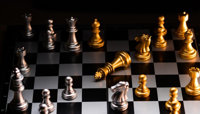 Fallen gold king in a strategic chess match. Checkmate.