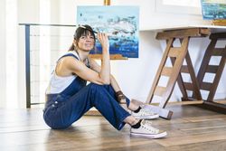 Portrait of a woman artist siting on the floor while looking at camera.