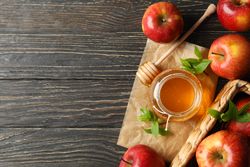 Looking down at pot of honey with dipper and apples with copy space