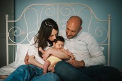 Parents hugging baby on bed