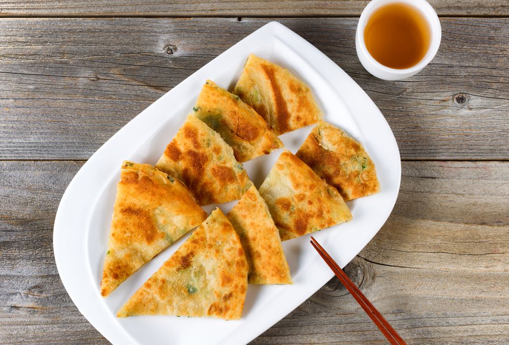 Fried Asian pancakes with tea in bowl on rustic wood