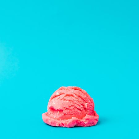 Scoop of pink ice cream on bright blue background