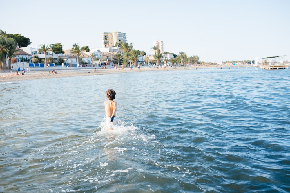 Boy walking in blue water of resort sea