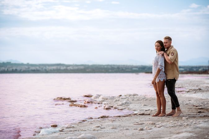 adorable couple standing on an amazing beach with pink water