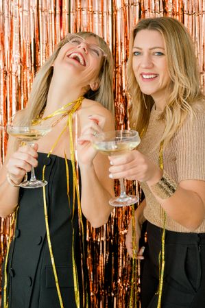Cheerful women with champagne celebrating New Year