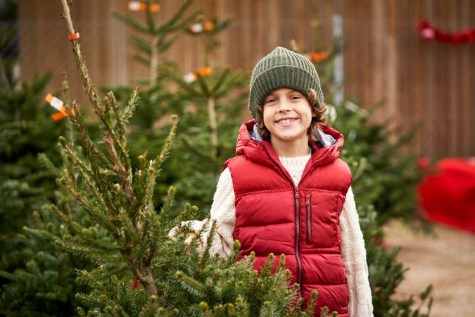 Happy kid smiling at camera in coniferous trees market