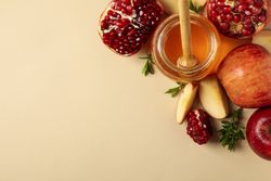 Looking down at open pomegranate, honey pot and sliced apple with copy space