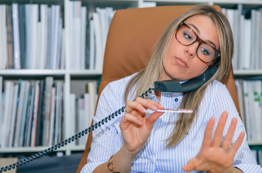 Blonde woman filing her nails at desk