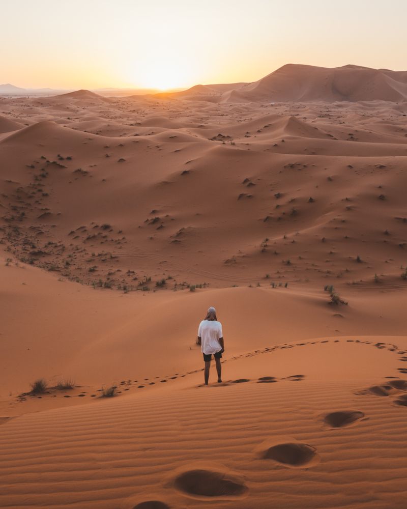 man in white summer t-shirt walking in desert