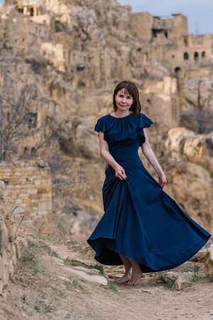 Woman in long blue dress standing near abandoned village
