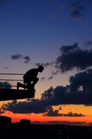 Male pretending to dive off ledge at dusk, vertical