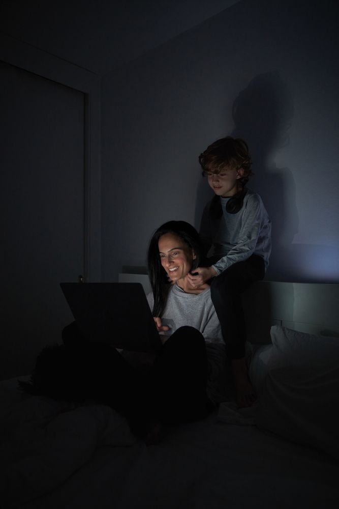 Mother and son surfing netbook in bedroom at night