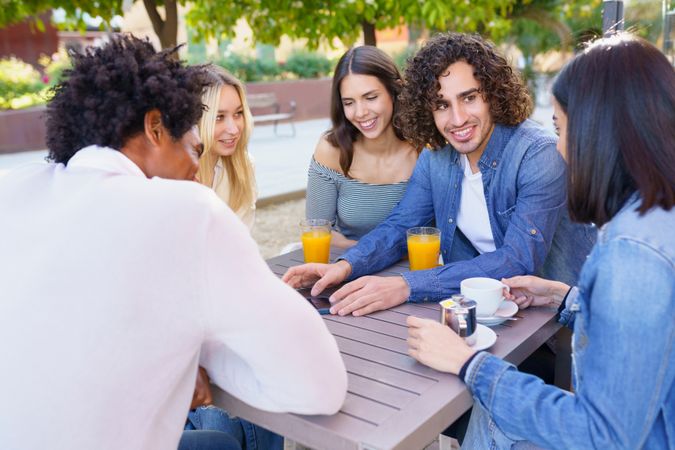 Group of friends having coffee and juice outside and chatting