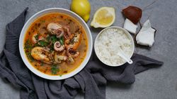 Soup of octopus and shrimps near rice and lemon