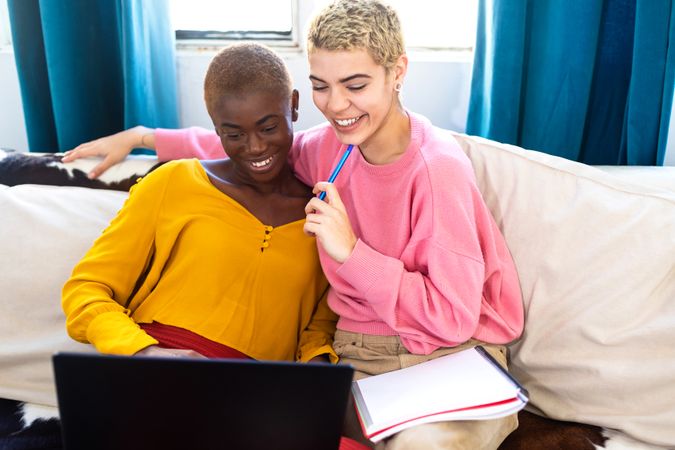 Female friends with a laptop resting on couch at home