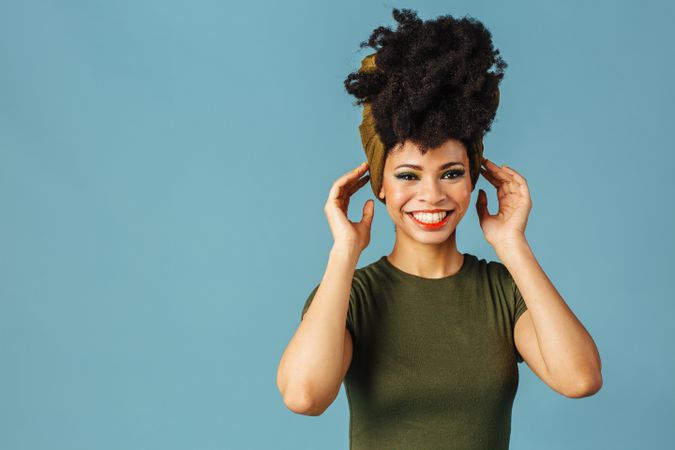 Studio shoot of Black woman smiling with her hands to her head