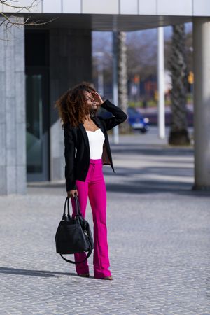 Female in bright pink trousers and handbag strolling outside