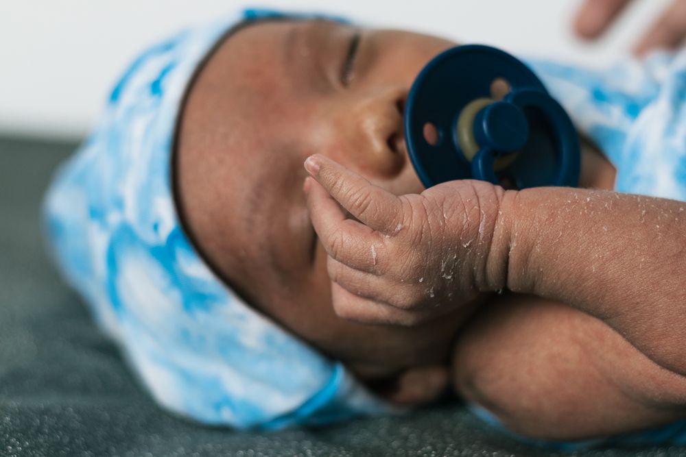 Newborn baby wrapped on soft blanket with pacifier