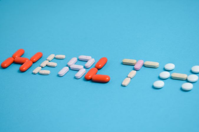 Various pills spelling the word "HEALTH" on blue background