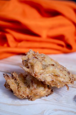 Two bakwan, fried snacks are on a table with an orange cloth