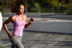 Woman with afro hairstyle running outside in sports wear
